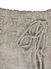 Primer plano de la cintura de la falda de alpaca, con dibujo de trenzas, cordones ajustables y borlas finales, modelo Angy.